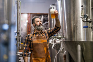 Brewer with a pint among fermentation vessels